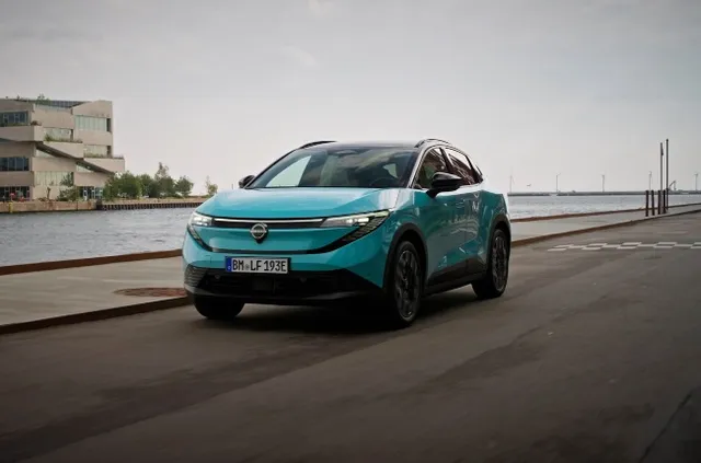 Nouvelle Nissan Leaf 2026 crossover électrique turquoise, trois quarts avant au bord de l'eau