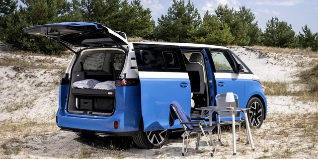 Le Volkswagen ID. California Cruise, van aménagé électrique dérivé de l'ID. Buzz, hayon ouvert sur son couchage, installé en mode camping sur le sable
