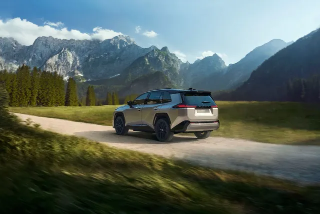Toyota RAV4 hybride rechargeable 2026 vu de trois quarts arrière sur une route de montagne
