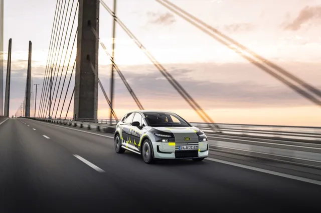 L'Audi A2 e-tron en livrée camouflage de prototype, roulant sur un pont au coucher du soleil