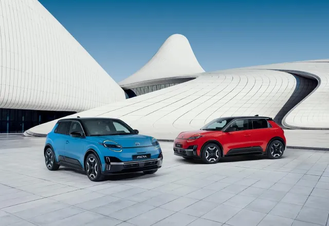 Deux Nissan Micra électriques, une bleue et une rouge, stationnées devant un bâtiment moderne