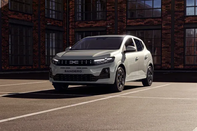 Dacia Sandero restylée grise de trois quarts avant devant un bâtiment industriel