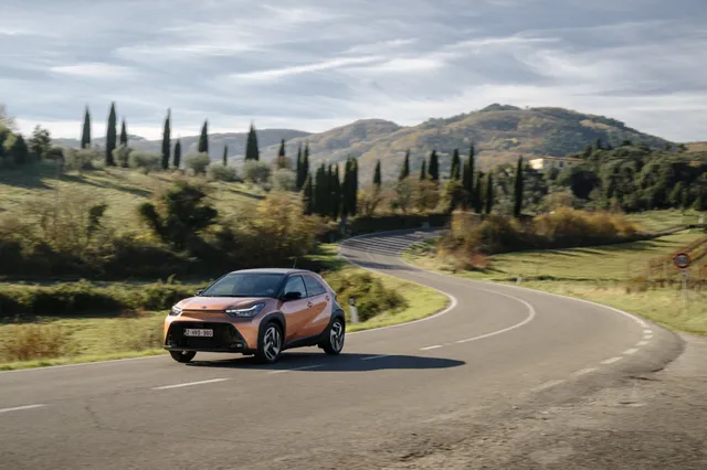 Toyota Aygo X Hybride 2026 de couleur cannelle sur une route de campagne