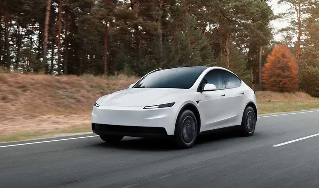 Tesla Model Y 2026 blanche roulant sur une route bordée d'arbres