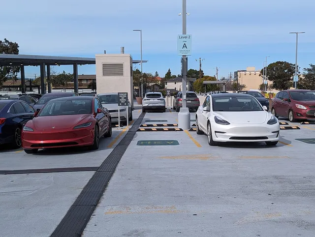 Deux Tesla Model 3 Highland, une rouge et une blanche, sur un parking