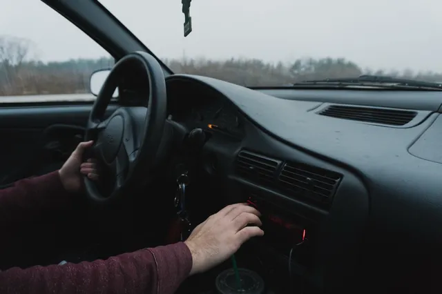 Conducteur réglant l'autoradio de sa voiture sur le tableau de bord