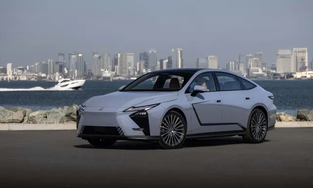 Lexus ES 2026 blanche de trois quarts avant, garée face à une baie et une skyline