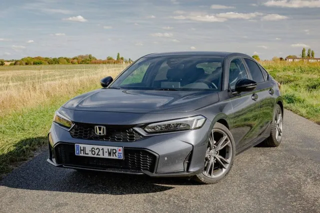 Honda Civic e:HEV 2026 grise de trois quarts avant sur une route de campagne