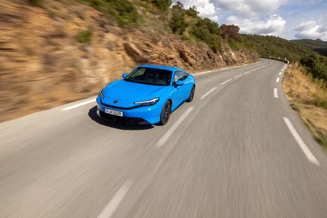 Honda Prelude e:HEV bleu Racing en mouvement sur une route de montagne