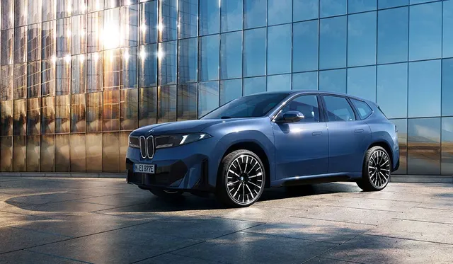 BMW iX3 Neue Klasse électrique de trois quarts avant devant un immeuble vitré