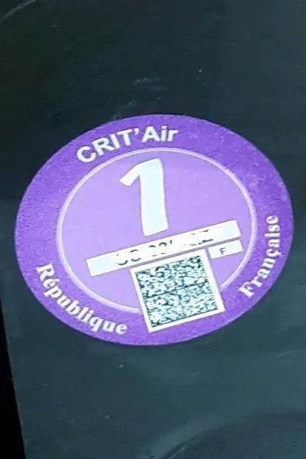Vignette Crit'Air 1 violette collée sur un pare-brise de voiture