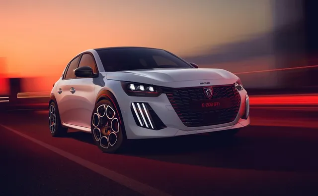 Peugeot e-208 GTi 2026 blanche de trois quarts avant, jantes 18 pouces Michelin et calandre GTi à liseré rouge